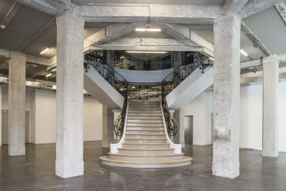 Vaste espace industriel avec colonnes en béton brut, sol en béton poli gris