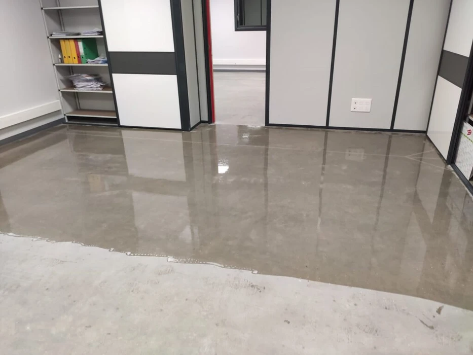 Vaste espace industriel vide, sol en béton ciré hautement poli à finition miroir, reflets lumineux intenses