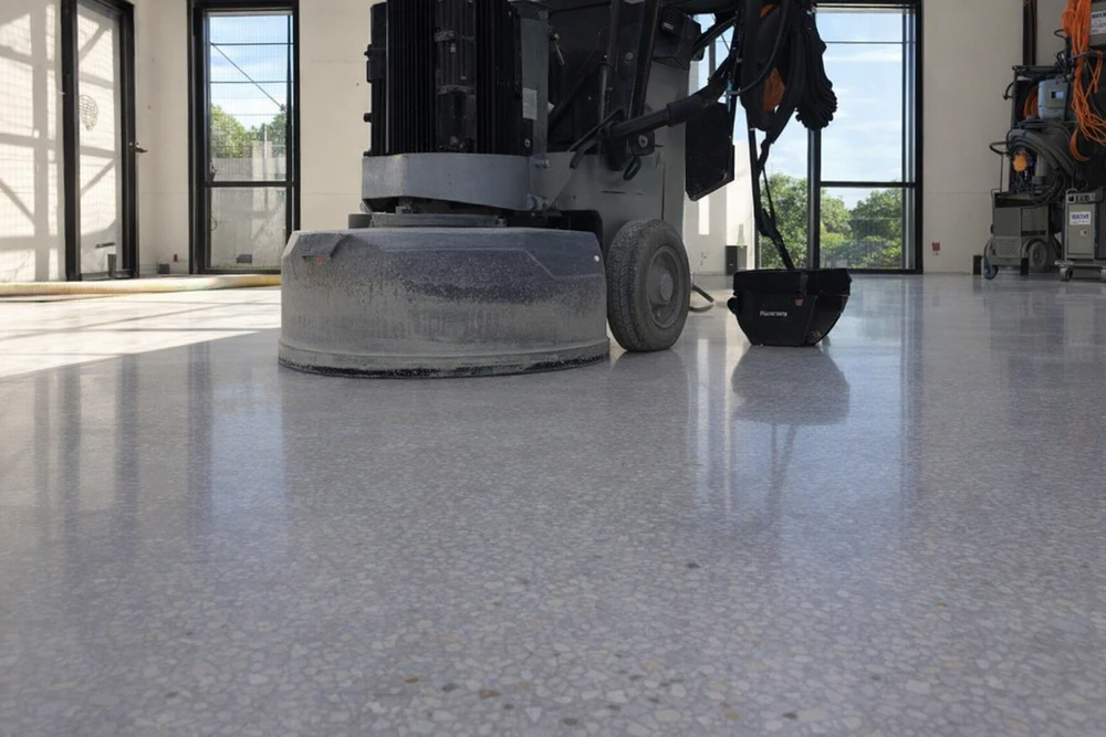 Vaste espace industriel vide, sol en béton ciré hautement poli à finition miroir, reflets lumineux intenses