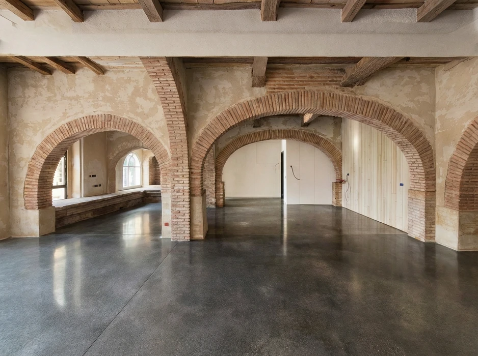 Espace commercial vide en cours de rénovation, sol en béton ciré poli réfléchissant, murs blancs avec zone peinte en anthracite et teal