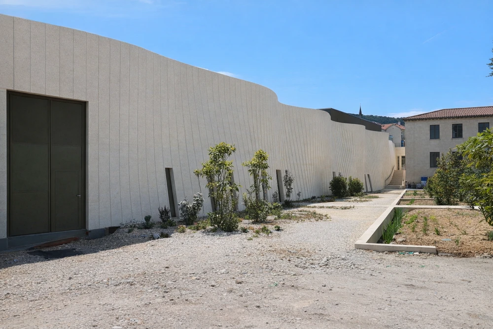 Couloir moderne résidentiel avec sol en béton poli brillant, murs blancs, miroir circulaire noir, jardinière métallique avec plante verte
