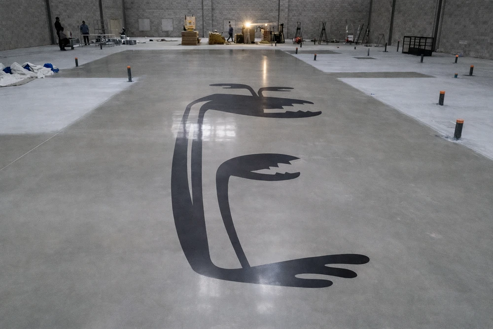 Vaste espace commercial vide de type showroom, sol en béton poli brillant, plafond à dalles acoustiques noires avec spots LED encastrés et structure métallique apparente