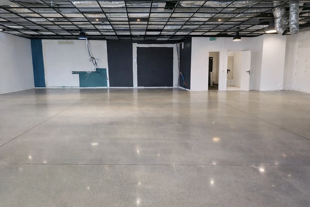 Vaste hall industriel en béton poli réfléchissant, en cours d'aménagement