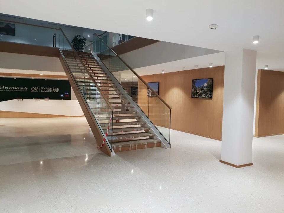 Ouvrier en tenue de travail multicolore utilisant une ponceuse &agrave; b&eacute;ton &eacute;lectrique dans un espace int&eacute;rieur en construction