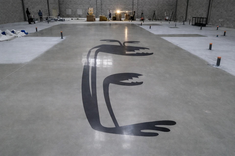 Intérieur résidentiel ou commercial moderne montrant un sol en béton poli gris clair, parfaitement lisse et brillant, présentant une teinte naturelle homogène sans vernis apparent. Le sol doit être visible sur une surface importante en premier plan, en contraste avec les murs et éléments de décoration (mobilier minimal, parois claires ou baies vitrées en arrière-plan). La lumière naturelle doit mettre en évidence l'éclat caractéristique et la profondeur du béton poli. L'image doit illustrer clairement la transformation de caractère d'un espace intérieur grâce au béton poli.