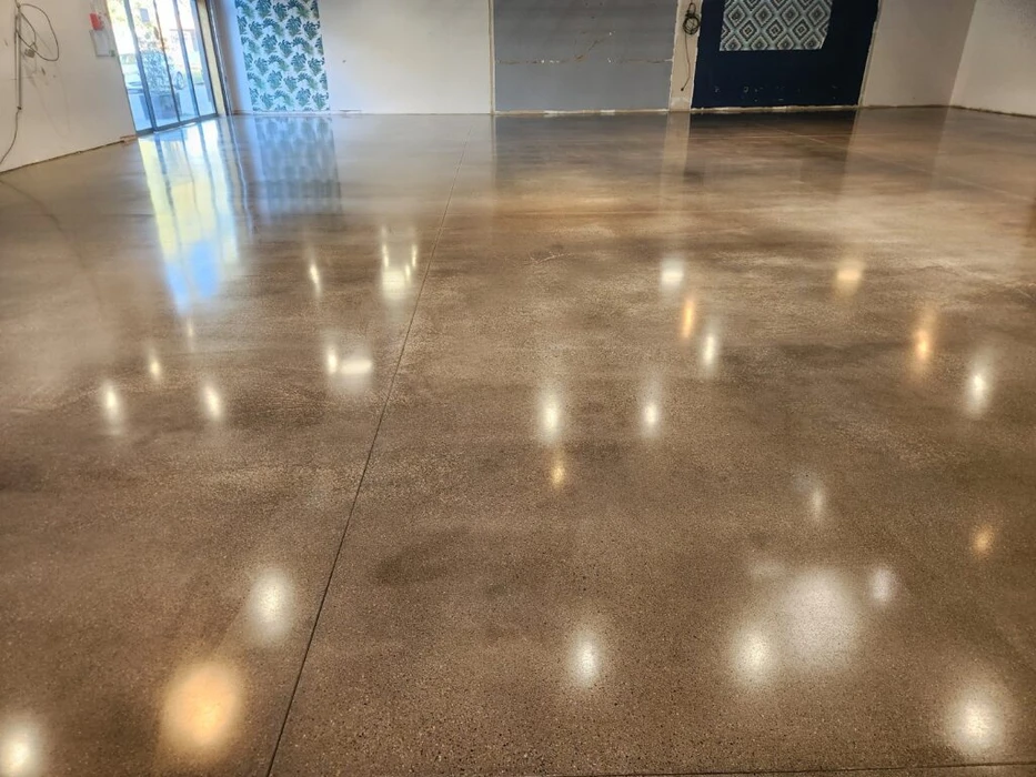 Gros plan détaillé d'une surface de sol en terrazzo poli montrant la brillance haute du poli, les veines naturelles des granulats de marbre blanc et gris, la finition lisse et réfléchissante du matériau, photographié de manière à bien exposer la qualité de la texture et du brillant caractéristique du terrazzo.