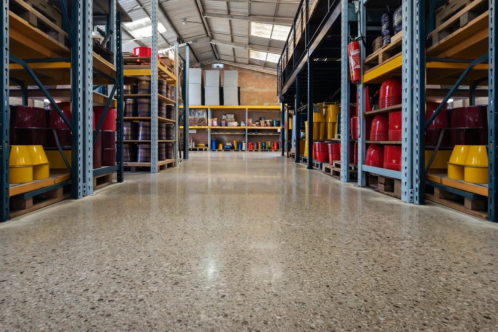 Gros plan détaillé d'une surface de sol en terrazzo poli montrant la brillance haute du poli, les veines naturelles des granulats de marbre blanc et gris, la finition lisse et réfléchissante du matériau, photographié de manière à bien exposer la qualité de la texture et du brillant caractéristique du terrazzo.