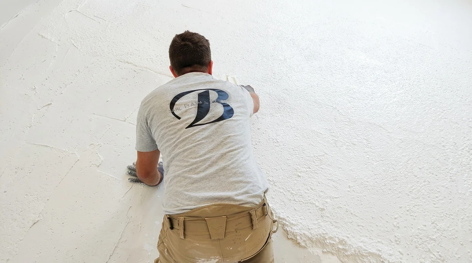 Espace commercial vide en cours de rénovation, sol en béton ciré poli réfléchissant, murs blancs avec zone peinte en anthracite et teal