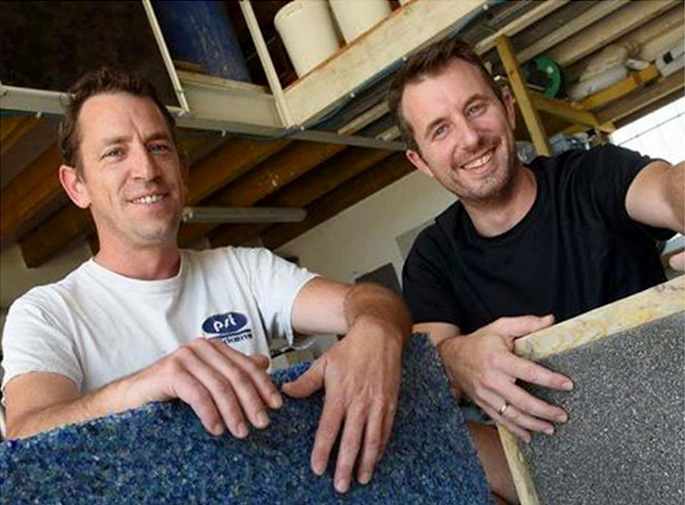 Ouvrier en vêtement blanc utilisant une ponceuse à béton électrique sur sol en béton brut dans un espace intérieur